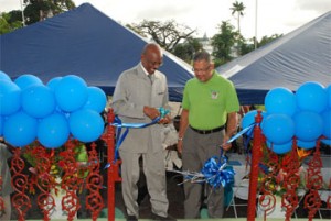 Left in photo is Mayor Hamilton Green as he performs the symbolic cutting of the ribbon in acceptance of the newly refurbished bandstand while Edwin Gooding, Managing Director of Republic Bank looks on. 