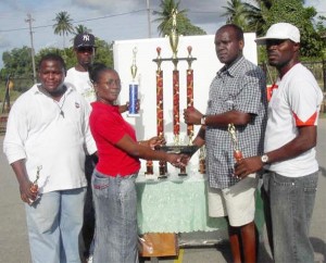 Beverly McDonald, secretary of Victory Valley Royals Basketball Club is seen handing over the James Brusche Trophy to LABA president Uborn Smith in the presence of other officials of the association. From left assistant secretary Quincy Cummings, organizing secretary Abdulla Hamid and public relations officer Floyd Martindale.