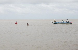 Mahase Prahalad and another farmer standing in waist-deep water in the mouth of the Abary River.