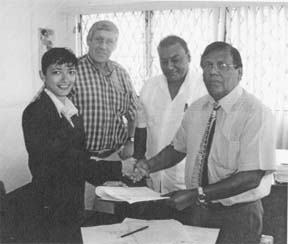 General Manager of the National Parks Commission Yolanda Vasconcellos and EPA Executive Director Doorga Persaud shake hands at the signing of the grant agreement. In the background are team leader of the GFA Consulting Group Ben ter Welle and EPA Director of the Natural Resources Management Division Dr Indarjit Ramdass. 