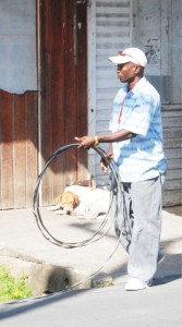 Picking up loose ends: This GPL employee was rolling up a section of the cable removed from a house yesterday, which had abandoned its metered connection to use an illegal one. (Photo by Jules Gibson)  