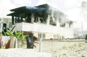 A fireman inside the house directs water to quell flames after fire struck at this Barr Street, Kitty home yesterday.  