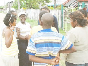 Shaundell Williams (wearing cap) stands among several residents yesterday afternoon who were offering their condolences and accounts of what happened on Thursday night.