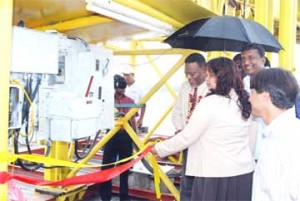 Prime Minister Samuel Hinds (left) cuts the ribbon to officially open the operations of the Guyana Sand Port company.