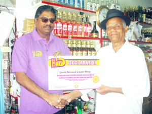 DDL representative Hargobin Hariram (left) presents the ID Declaration Certificate to the proprietor of the David Persaud Liquor Shop Durgo Persaud. 