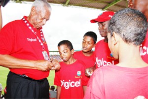 Cricket great Lance Gibbs signing autographs for the boys. (Digicel photo)