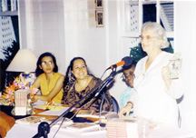 Janet Jagan holds up a copy of the revised version of Martin Carter’s Selected Poems at the launch in Cara Lodge. At left sit members of Red Thread Women’s Press which published the work.