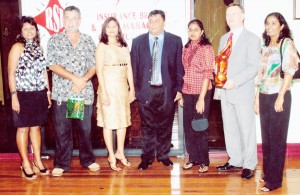 Raj Singh and his wife take time out to pose with some of the attendees and awardees at the anniversary ceremony. From left to right-  Elizabeth Cox, Stanley MacIntosh (the company’s first customer), Nalini Singh (wife of Raj Singh), Raj Singh,  Oma Singh (awarded for 10 years of service), Alan Thomas  (CEO of the London-based New World Marine Insurance Consultants),  and Sharmila Seeram (awarded for 5 years of service). 