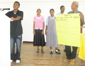 A youth presenting the findings from his group in the presence of other members during the peer pressure workshop.