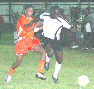 Camptown’s Anthony Belfield (in white) is marked closely by Fruta Conquerors’ Paul Bobb in their Milo Under-21 semi-final match at the Tucville Playfield on Wednesday. (Orlando Charles photo)