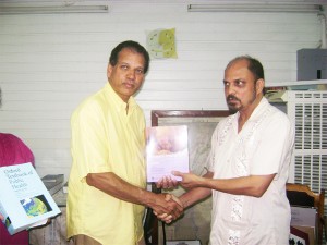 In photo, Dr Bheri Ramsaran (right) receives one of the books from Roland Rampat.