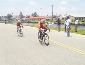 Robin Persaud crosses the finish line ahead of Tony Simon to win the third and final leg of the 12th Annual Cheddi Jagan Memorial cycle road race in Essequibo yesterday.
