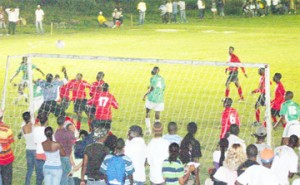 The goal mouth scrimmage which resulted in the second goal being scored for Ann’s Grove (green and white) against Buxton United (red and black).  (Orlando Charles photo)  