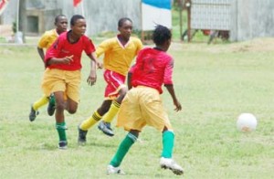 Coca Cola U-15 Action! These Uprising players (in red) try to move on the ball, while being challenged by their opponents yesterday at the Tucville Playfield in one of the semifinal encounters.