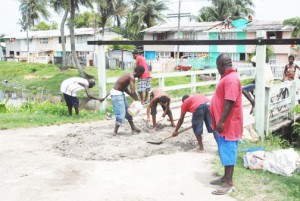 Helping themselves: Residents of West La Penitence patching a pothole in the road and sprucing up a bridge in their area yesterday morning (Photo by Jules Gibson)