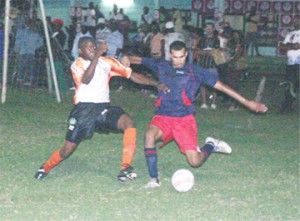 Cougars’ Ron Wilson (right) attempts to let loose a left foot shot, even as Sunburst Camptown’s Kris Camacho tries to intercept. (Orlando Charles photograph)  
