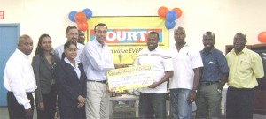 Country Manager of Courts Guyana Inc. Lester Alvis (centre) hands over the sponsorship cheque of $500,000 to GFA’s President Troy Mendonca (4th R) as members of Courts and the GFA share the moment. Standing to the extreme right is Banks DIH PRO Troy Peters. 