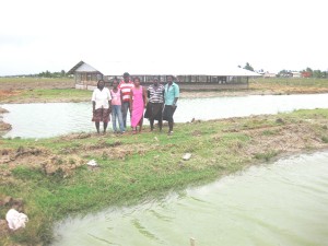  Lloyda Angus and other members standing near two of the fish ponds. In the background is one of the chicken pens.  