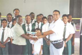 Physical Education teacher at Bishops High School Ms. Kendra Squires receives a box of shuttle cocks from president of the Guyana Badminton Association (GBA) Gokarn Ramdhani while students of the school look on. 