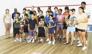 The various prize winners strike a pose with their spoils along with Guyana’s squash queen Nicolette Fernandes (back row left) and national coach Carl Ince (next to Fernandes). An Aubrey Crawford photograph.  