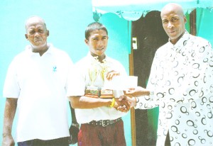 Former national bantamweight boxing champion Jeff Roberts, right, hands over a monetary donation to cycling champion Neil Reece of Berbice. At left is Reece’s coach Randolph Roberts.   