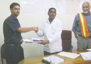 Kiran Nauth (left) of H. Nauth and Sons contracting firm and Permanent Secretary of the Ministry of Local Government, Sewchan shake hands after revealing that the firm had been awarded the contract for the construction of the access road to the Haags Bosch landfill site. At right is project manager, Walter Willis. 