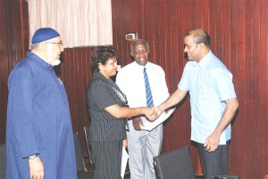  President Bharrat Jagdeo (right) congratulates Savitri Sukhai after she and Fazeel Ferouze (left), and Rev Nigel Hazel(second right) were sworn in as Integrity Commission members. 