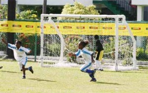 Uprising’s Keifer Brandt (Left) celebrates netting a goal against Western Tigers’ in their Pee Wee match yesterday at the Banks DIH ground, Thirst Park. (Orlando Charles Photo)   