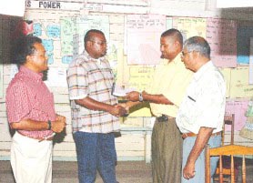 BNTF Project Manager Michael Singh (second from right) hands over the project document for the new Lusignan well to contractor Philmon Morren at the Lusignan Primary yesterday. Looking on are NDC Chairman Richard Bactowar (right) and consultant Paul Bernard. 