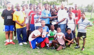 Sheldon Braithwaite is seen handing over some of the equipment to Fruta Conquerors’ U-17 custodian while members of the U-17 and U-11 teams along with coach Kirt Codogan (3rd left) look on. 