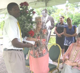 A student presenting the bouquet of flowers to Phyllis Carter 