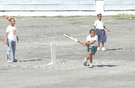 This St Angela’s student (centre) hits out during their run chase against St Andrew’s at the National Park Tarmac. (Orlando Charles photo)   