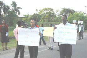 Trade unionist Lincoln Lewis (right) and social activist Mark Benschop (second from right) led a protest yesterday against the government outside the National Cultural Centre during the opening ceremony for the Caricom Heads of Government conference. 