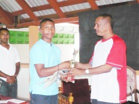 Carlos stands proudly as he receives his prize from the President of the Guyana Chess Federation. 