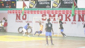 Flamingo’s Cordel Dowding (left) records his team’s fifth goal with 1:20s on the clock (top left) to go into the final half as he beats the Alpha United goalkeeper to the top bar in the Guinness Futsal Tournament at the Cliff Anderson Sports Hall Monday night. (Orlando Charles photo)  
