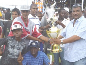 Chris Jagdeo, at right, receives the winning trophy in the three-year-event from a representative of Arjune Poultry Supplies.