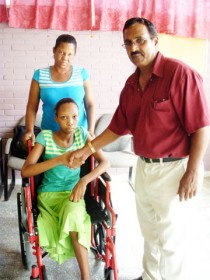  Fifteen-year-old Alicia Trim shakes hands with Rotarian Basil Jaipaul as her mother Brenda Harris looks on. Trim was the recipient of a wheelchair courtesy of the Club. 