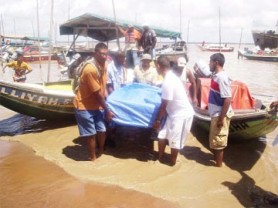 Persons removing the body of Dweive Kant Ramdass from the boat at Parika beach yesterday.  