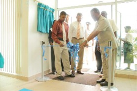 Prime Minister Sam Hinds (right) cuts the ribbon at the formal opening of the new Republic Bank branch at Anna Regina while Managing Director Edwin Gooding (centre) and other representatives look on. 