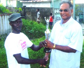 Rudolph Mitchell receives a trophy from Director of Sport, Neil Kumar, after scoring a century of race walk wins last Saturday. 