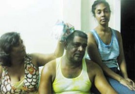 Parasram Ramnarace’s sister Gaitri Singh (left) applying an ice pack to the wounds on his head as his wife, Ahilia sits by his side. 