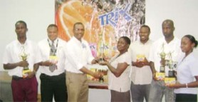 Bryden and Fernandes Inc. Marketing Coordinator, Mark Kendall (3rd L), hands over the Trix Trophy to Fruta Conquerors representative Peggy Julien (centre) while representatives of other top teams, the GFA and Bryden and Fernandes Inc. look on. 