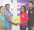 Guyana Telephone and Telegraph Company (GT&T) representative Rhonda Johnson presents Abigail McDonald (right) with an X Box console which will go towards the fund raising raffle competition in October. Moen Gafoor stands far right. 