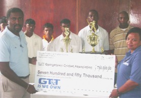 GT&T’s Marketing Officer  Phaedra Cramer-Phillips presents the cheque for the tournament to GCA President Alfred Mentore yesterday at GCC’s main pavilion. Looking on are some cricketers from ECC and officials of the GCA. (Orlando Charles photo)  