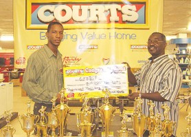 Public Relations Officer Pernell Cummings gives a cheque in  the amount of $70,000 to President of the Guyana Amateur Body Building and Fitness Federation, Frank Tucker.  