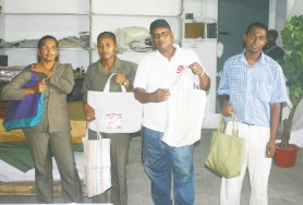 A.H.&L Kissoon staffers displaying a selection of the shopping bags