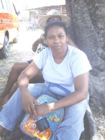 Sandra Beharry taking refuge under a tree while fire ravaged her home at Rose Hall yesterday.