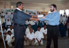 Shaikah Moeen Ulhack (right), receiving the checque from Kayum Khan. In background, students of the CIOG look on. 