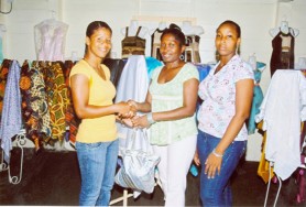 Gileon James of Wilo’s Bridal and Fabric Boutique presents Guyana world champion boxer Shondell Alfred her gifts in recognition of her winning a world title. Also in the photo is an employee at the store.   