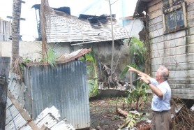 Jerome De Freitas recounting yesterday the heroic acts of the fire-fighters as he stood in his backyard. To the left of the photograph is the fence which was damaged during the battle to contain the blaze. (Jules Gibson photo)